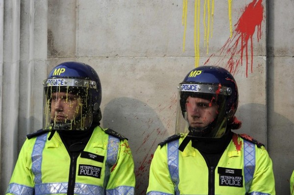 Policemen splashed with paint stand on guard outside a Top Shop store during a protest organised by the Trades Union Congress, in central London